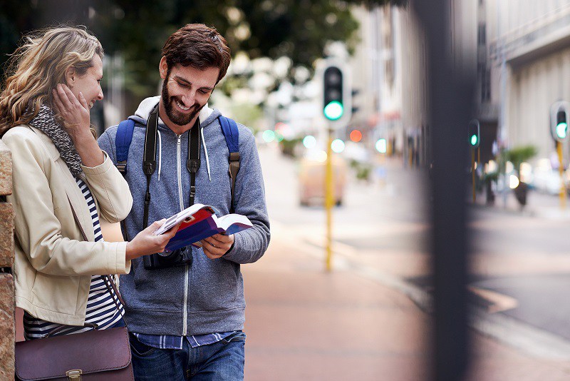 travel couple walking around city on vacation with guide book having fun